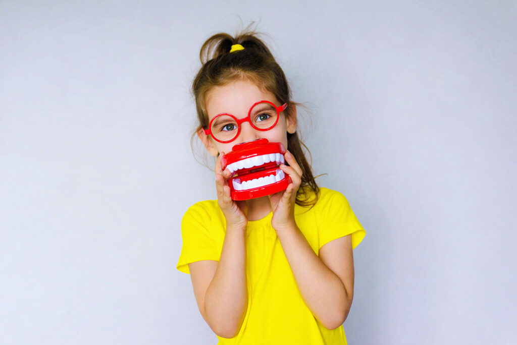niña en situación divertida sujeta boca de plástico en el dentista