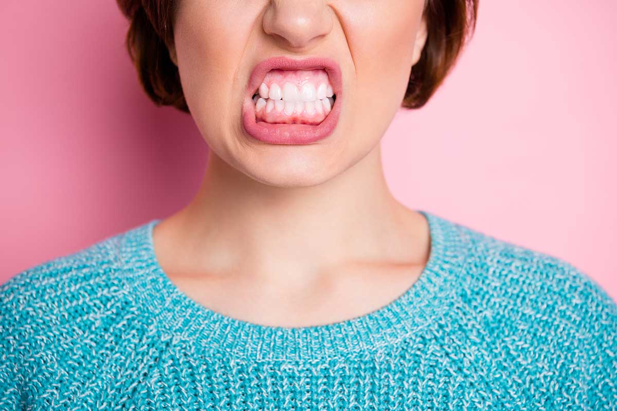 Mujer abre la boca y aprieta los dientes muestra dolor en las encías
