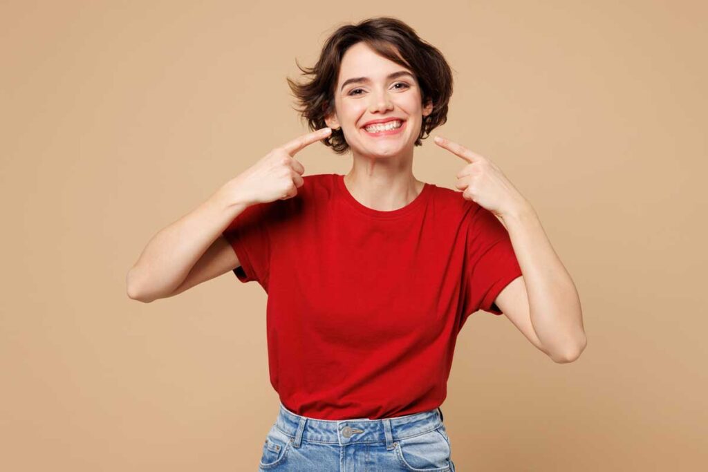 Mujer sonriente señalando su boca con ambas manos