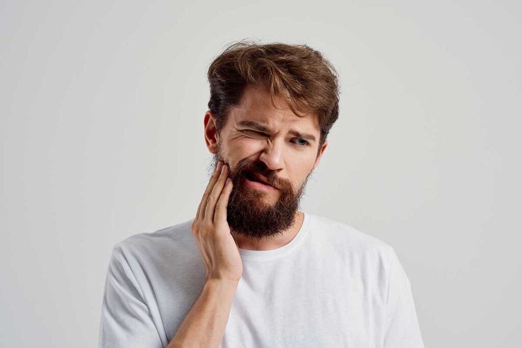 hombre con tensión mandibular masajeándose el rostro